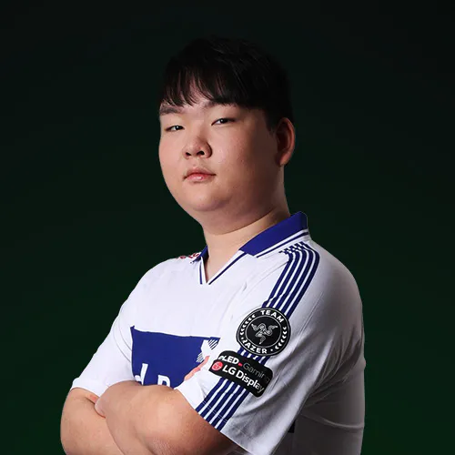 Young man in a white esports jersey with blue accents, arms crossed, standing confidently against a dark background.