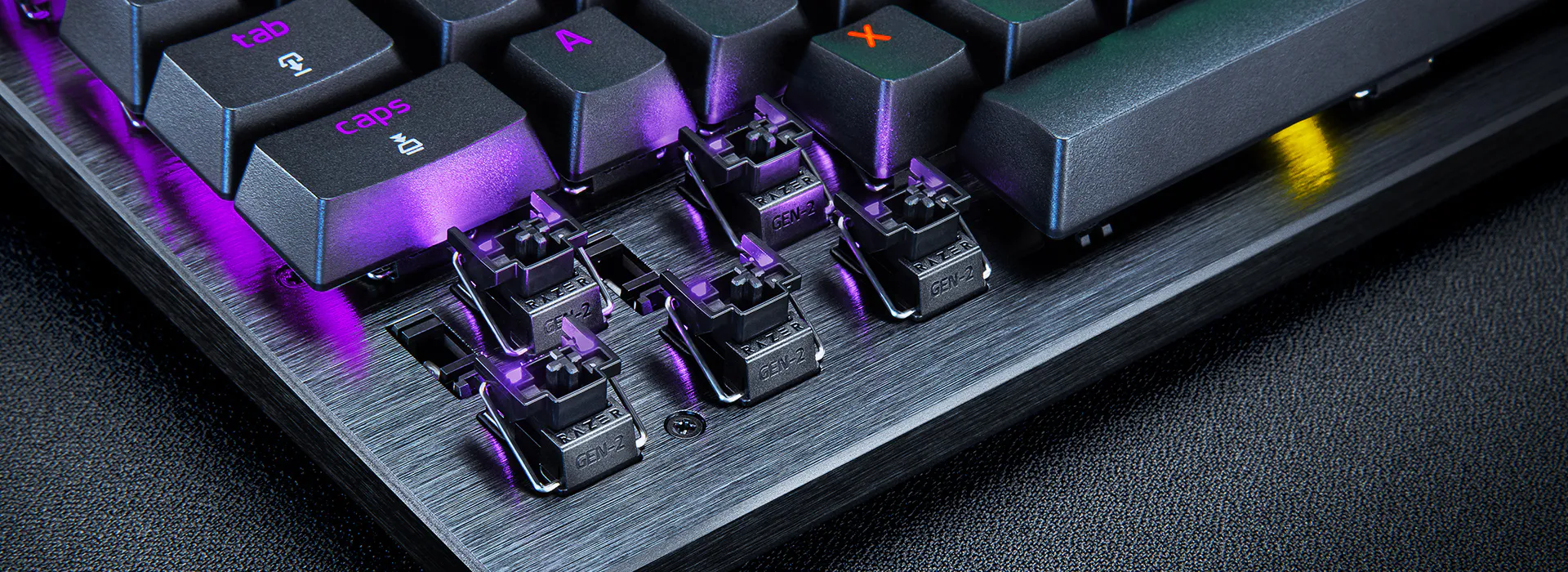 Close-up of a mechanical keyboard showing removed keycaps and switches, with purple backlight reflections on a brushed metal base.