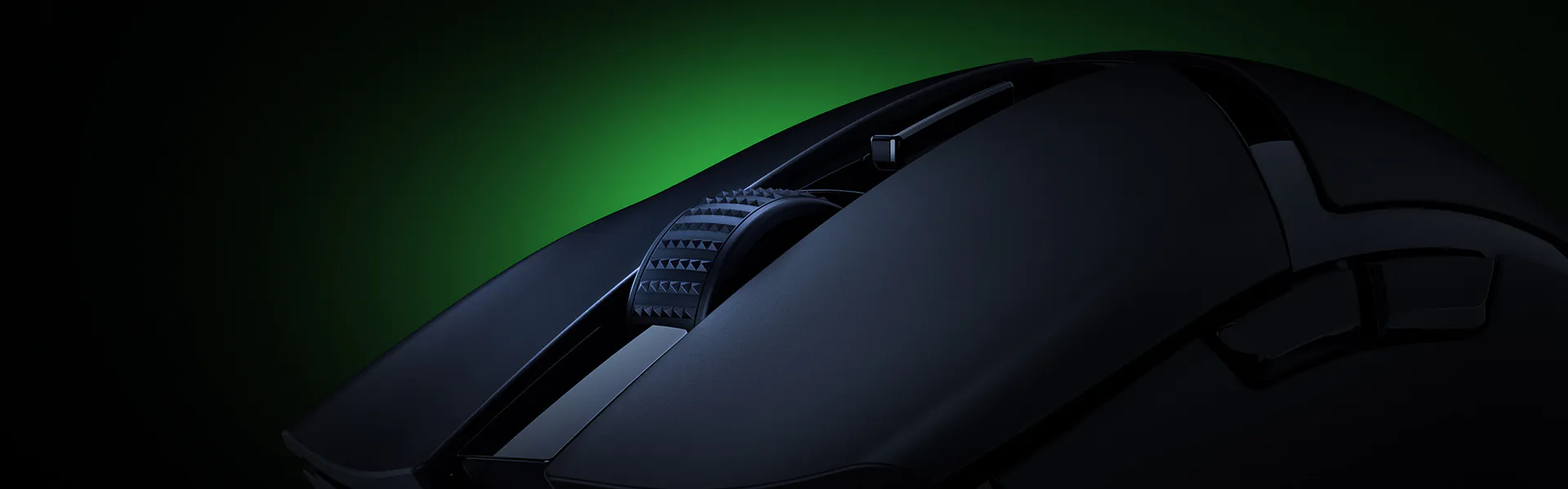 Close-up of a black computer mouse with two scroll wheels and textured grip, set against a dark background with a greenish glow.