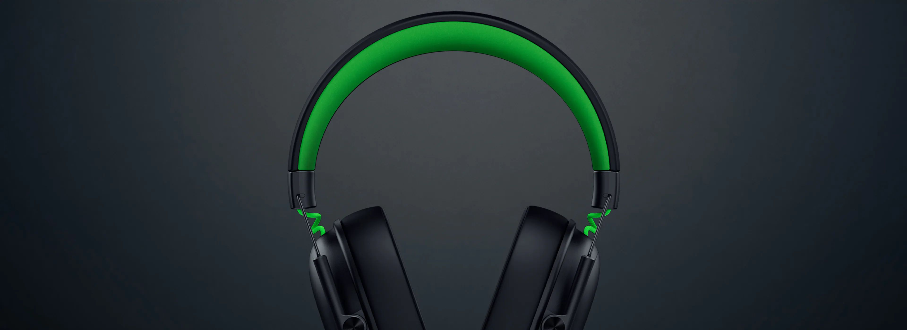 Wireless over-ear headphones with black ear cups, a headband illuminated in green, on a dark background.