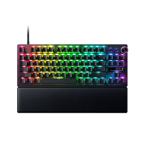 A multicolored RGB gaming keyboard with a wrist rest, featuring illuminated keys in rainbow pattern, volume controls, and a wrist rest.