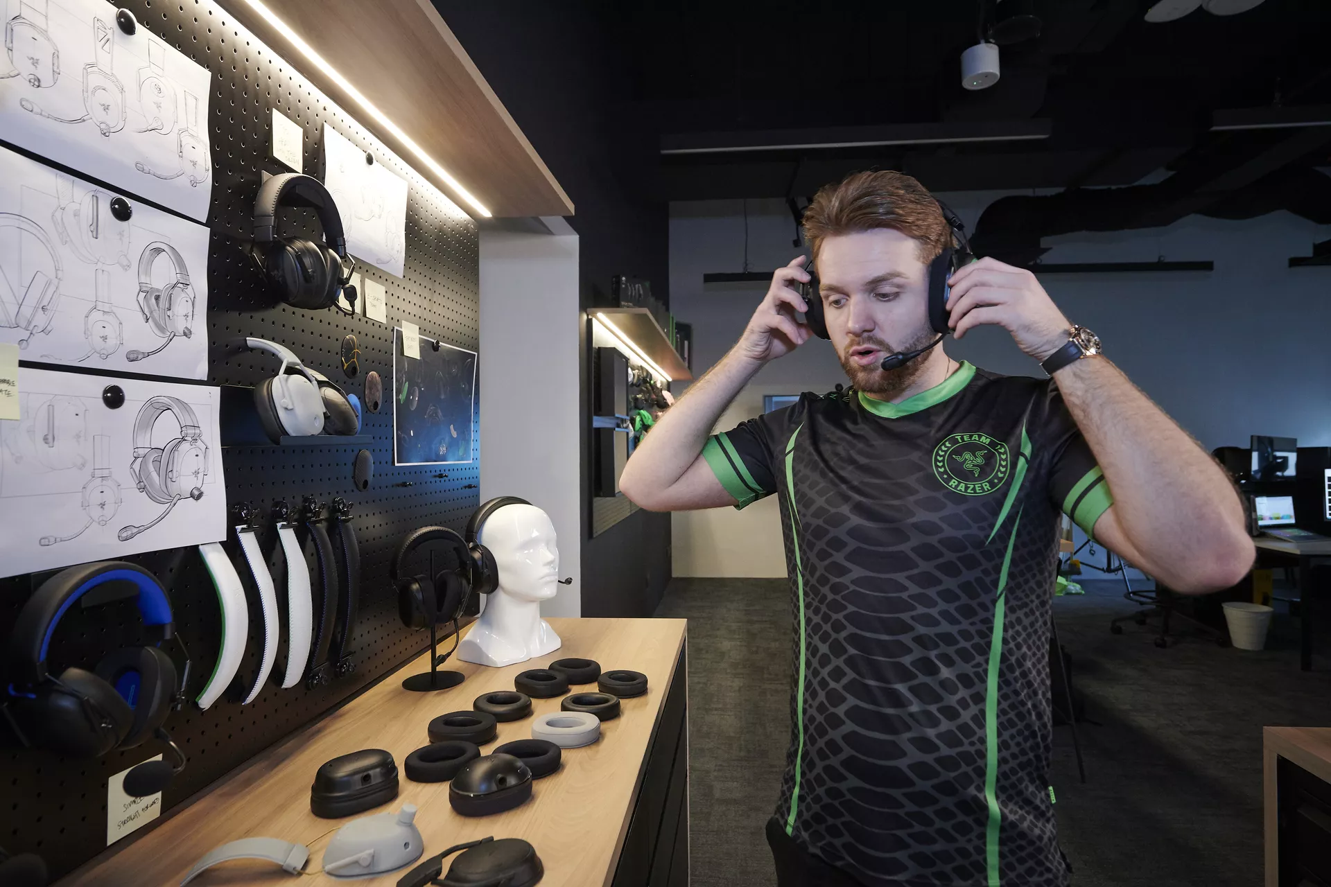 NiKo tests different Razer headset prototypes in a design lab, surrounded by ear cushion samples and headset concept sketches.