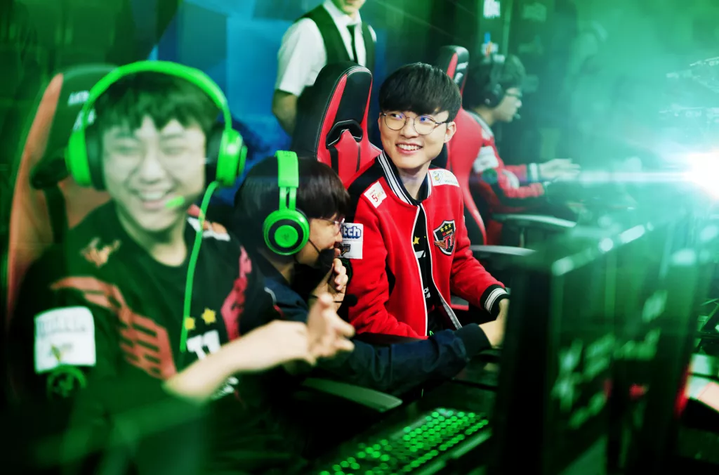 Faker with teammates in an esports match setup, wearing Razer headsets and competing on stage.