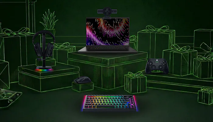 Gaming setup with RGB keyboard, mouse, headphones on stand, webcam, Xbox controller, all surrounded by green neon gift boxes, on a dark background.