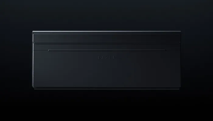 A sleek, black Razer laptop closed on a dark background with the Razer logo faintly visible.