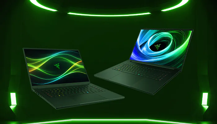 Two gaming laptops with Razer branding are displayed in a green-lit room, showcasing colorful, neon-themed screens.