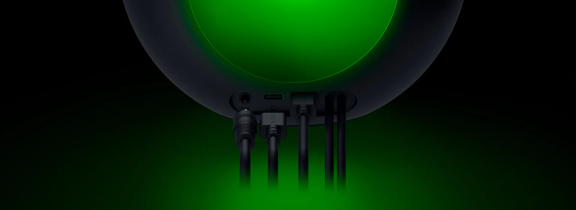 Back view of a black electronic device with multiple cables connected, including AUX, USB-C, and power, illuminated with green lighting.