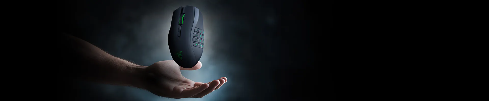 A hand holds a gaming mouse with green lighting, multiple buttons, and a textured grip against a dark background.