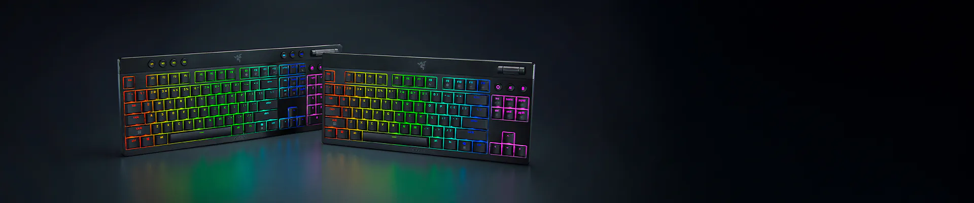 Two RGB backlit mechanical keyboards, black, showing colorful illuminated keys on a dark surface.