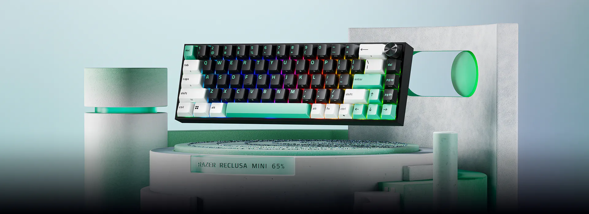 RGB mechanical keyboard with rainbow backlight mounted on a stand labeled "Razer Reclusa Mini 65%" with colorful cylindrical props around.