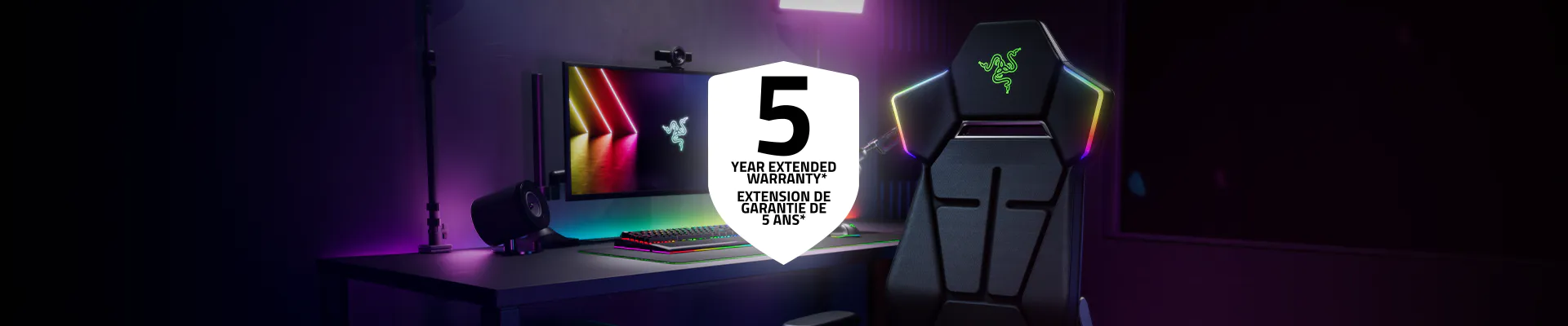 Gaming setup with a monitor, keyboard, speakers, and Razer gaming chair, featuring a "5 Year Extended Warranty" label.
