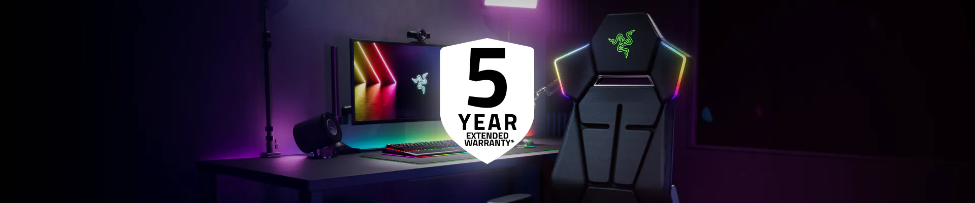 A gaming setup with a high-tech chair, RGB-lit monitor, keyboard, and speakers, with a prominent "5 Year Extended Warranty" badge.