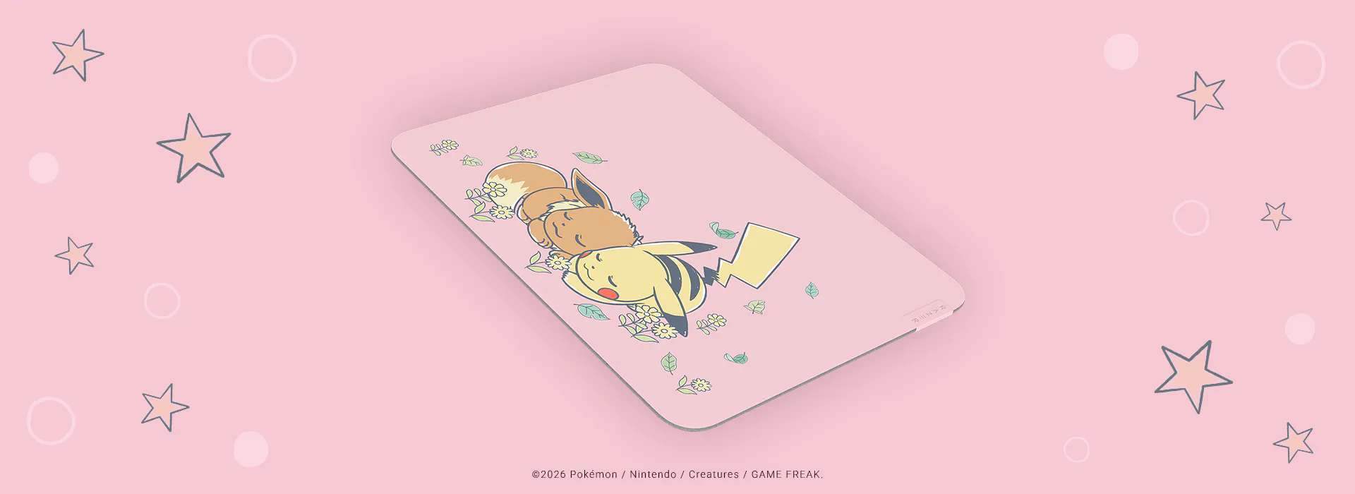 A pink mouse pad features Pokémon Pikachu, Eevee, and Raichu sleeping surrounded by leaves and flowers, with a subtle star and circle background.; ©2026 Pokémon / Nintendo / Creatures / GAME FREAK.