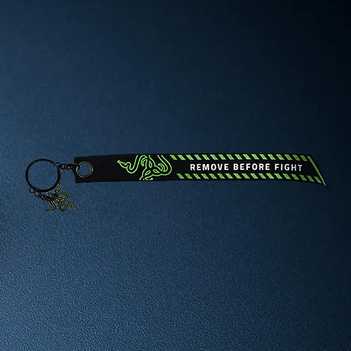 A black wristband with a green Razer logo, warning text "REMOVE BEFORE FIGHT," and a small charm on a metal keyring.