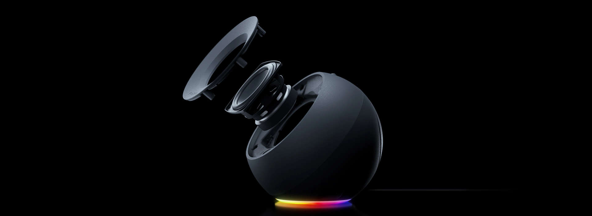 Wireless speaker with a spherical shape, top lid open showing internal components, colorful LED light ring around base.