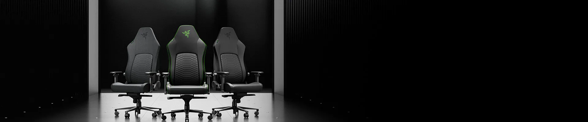 Three black gaming chairs with green accents and the Razer logo are arranged on a reflective black surface against a dark background.