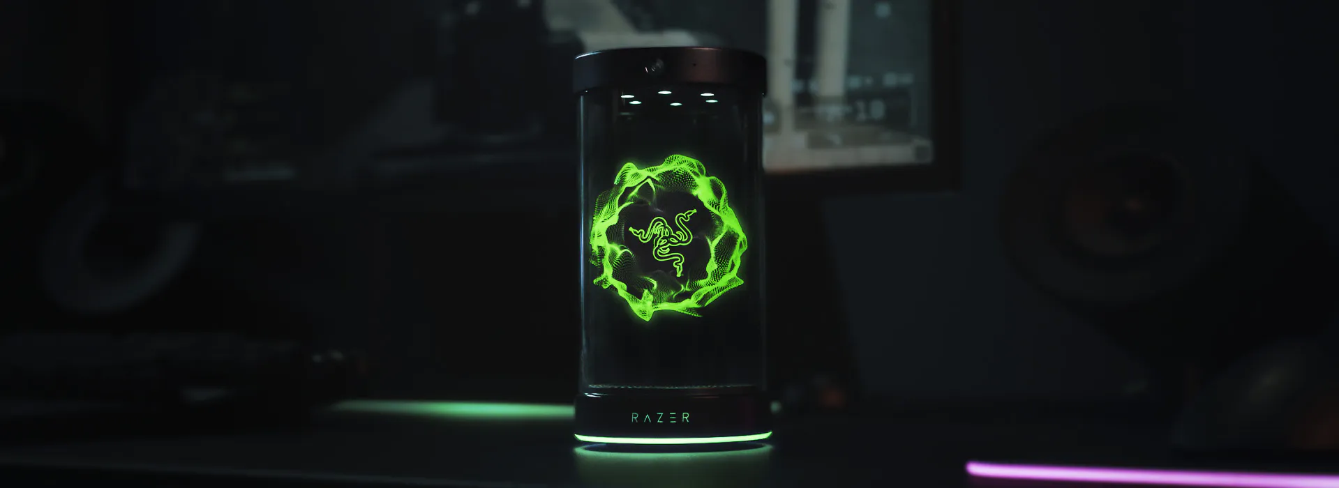 LED-lit cylindrical object with Razer logo, displaying a green, glowing snake design in a dark environment.