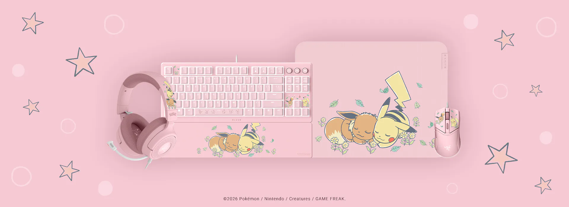 Pink Pokémon-themed keyboard, mouse, and headset set with Eevee and Pikachu illustrations on a pink background with stars. ©2026 Pokémon / Nintendo / Creatures / GAME FREAK.