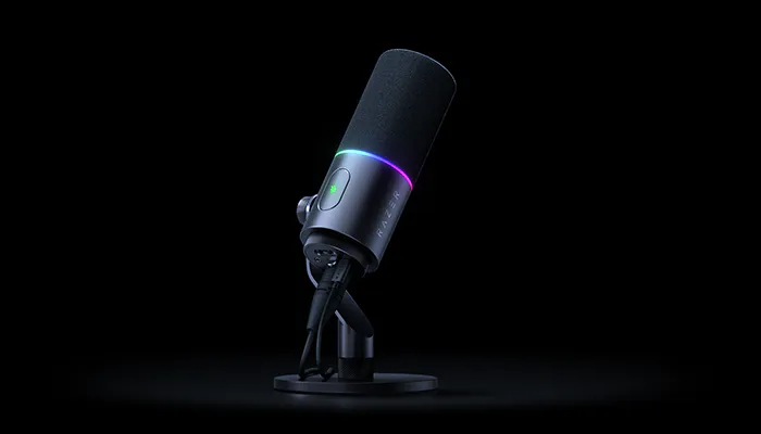 A black microphone with a colorful LED ring on a stand, featuring a power button, mounted on a round base against a black background.