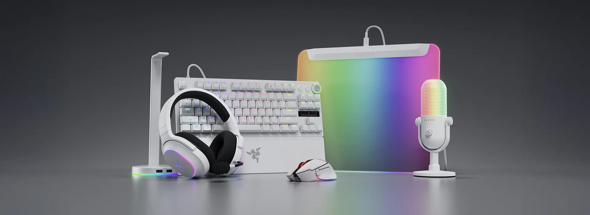 Colorful gaming accessories, including a keyboard, microphone, headset, mouse, controller, and a Razer-branded pad in a bright, minimal setup.