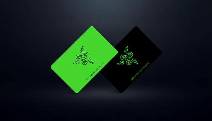 Two Razer gift cards, one green with a snake logo and "FOR GAMES. BY GAMERS." text, the other black with the same logo and text, slightly tilted.