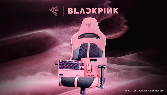 Pink gaming chair with Razer Blackpink branding, featuring a keyboard, mouse, and a gaming microphone, set against a pink and black background.