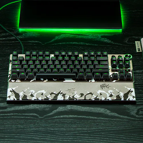 Mechanical keyboard with a silver and black design featuring a white spacebar decorated with black bat silhouettes; backlit keys with green lighting.