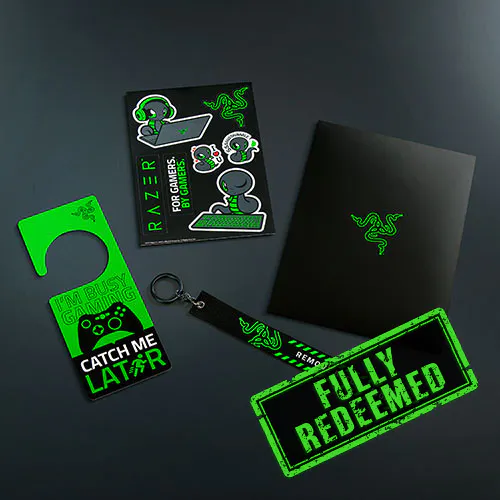 Set of Razer gaming accessories and merchandise with neon green and black designs, including stickers reading "FULLY REDEEMED" and "CATCH ME LAT R".