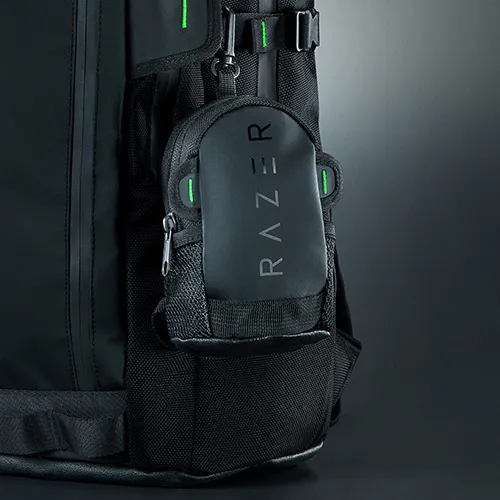 A black backpack with a small attached pouch labeled "RAZER," featuring green accents, zippers, and mesh pockets.