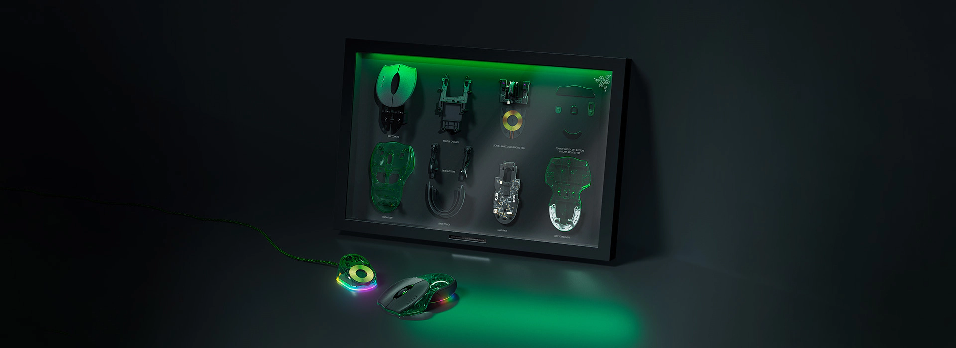 Disassembled tech parts with labels on display, connected with RGB-lit gaming mouse, keyboard, and trackball, illuminated by green lighting.